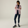 Persona in piedi con le braccia incrociate, indossa una giacca lilla chiaro con zip, top nero, leggings blu scuro, calzini grigi e sneakers blu scuro, sfondo chiaro uniforme