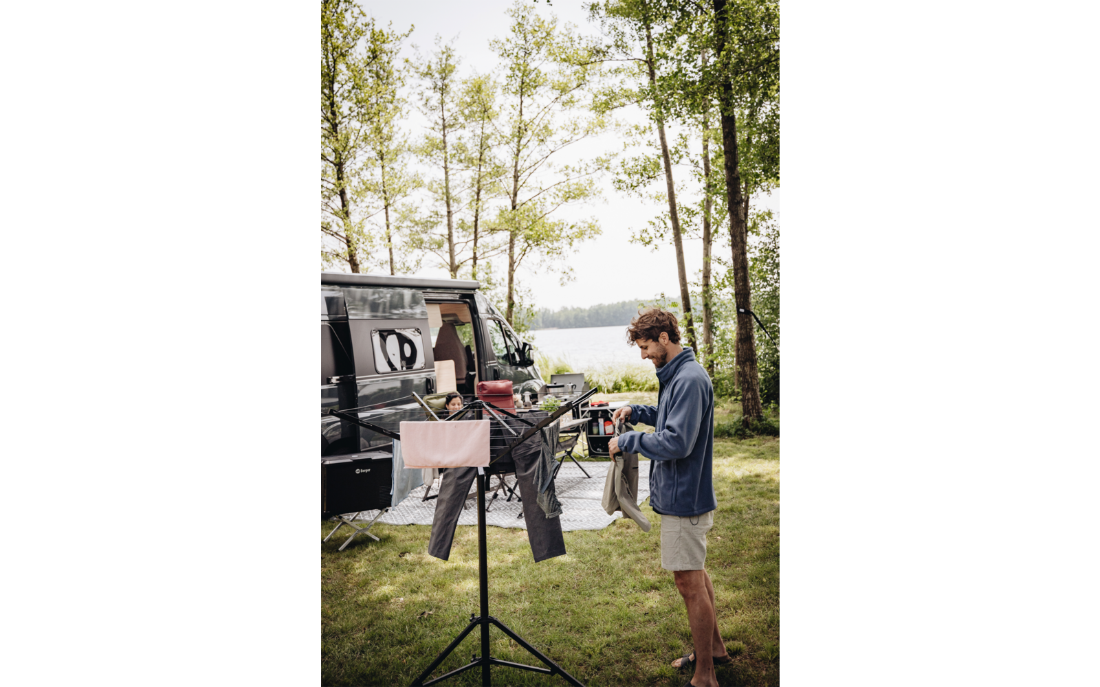 Deux hommes cuisinent en plein air sur un barbecue de camping à côté d'un véhicule