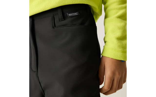 Nahaufnahme der Hüftpartie einer Person in schwarzen Hosen mit Regatta-Label und neon-gelbem Fleecepullover; rechte Hand sichtbar