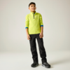 Ganzkörperaufnahme eines lächelnden Jungen, stehend vor hellem Hintergrund, mit neongrünem Pullover mit kurzem Reißverschluss, schwarzer Hose und schwarzen Sportschuhen