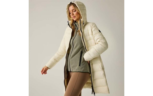 Donna con cappotto trapuntato lungo color crema con cappuccio, aperto sul davanti, maglione grigio strutturato e leggings beige, sfondo neutro