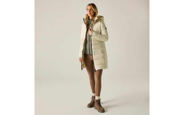 Donna con giacca trapuntata chiara al ginocchio con cappuccio, maglione grigio, leggings marroni e stivaletti marroni stringati su sfondo chiaro