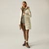 Donna con giacca trapuntata chiara al ginocchio con cappuccio, maglione grigio, leggings marroni e stivaletti marroni stringati su sfondo chiaro