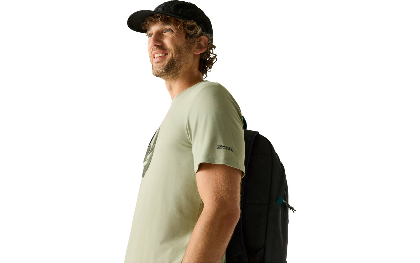Seitliches Porträt eines lächelnden Mannes mit schwarzer Baseballkappe, hellgrünem T‑Shirt und schwarzem Rucksack vor hellem Hintergrund