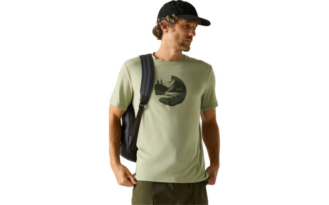 Person mit schwarzer Kappe, hellgrünem T‑Shirt mit dunklem rundem Motiv mit Bäumen und Bergen, schwarzem Rucksack, schaut nach links