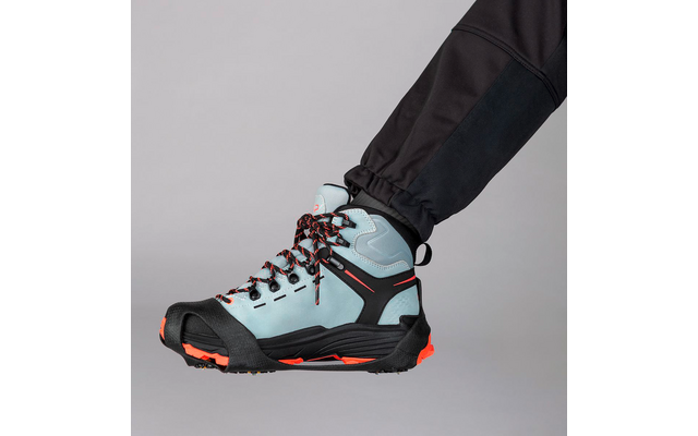 Hellblauer, knöchelhoher Schuh mit schwarzer und orangefarbener Sohle, schwarzem Zehenschutz und schwarz-orange gemusterten Schnürsenkeln, getragen an einem Bein in schwarzer Hose vor hellem grauem Hintergrund