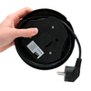 Hand holding black cable reel with power cord and plug