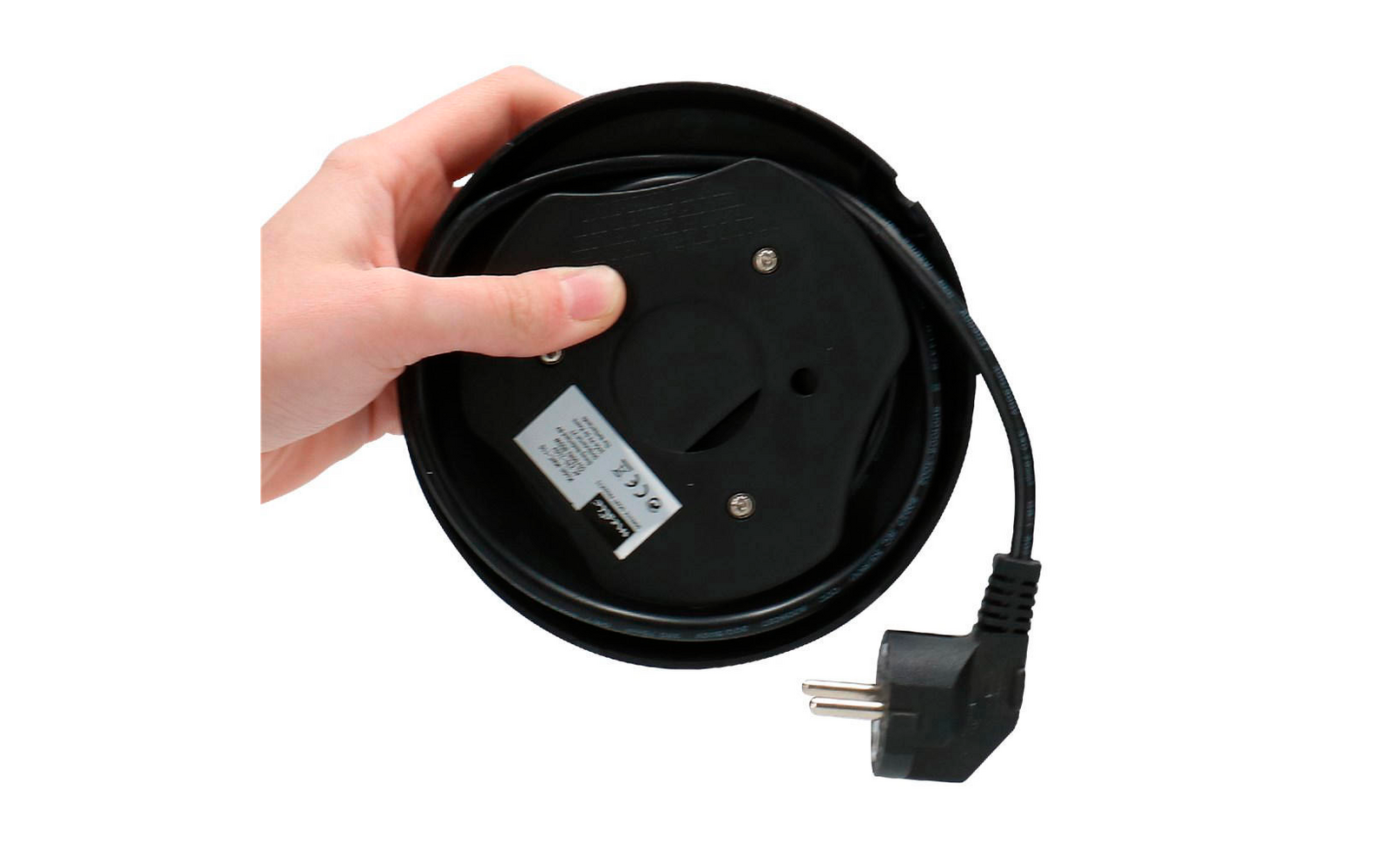 Hand holding black cable reel with power cord and plug