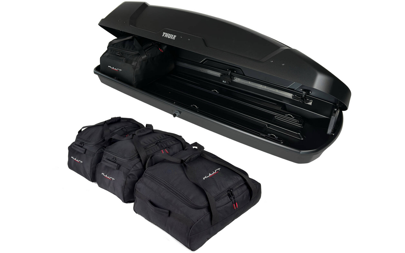 Geöffnete schwarze Dachbox mit sichtbarem Innenraum, davor vier schwarze Reisetaschen mit roten Details