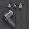Graues Handgerät mit zylindrischem Kopf und drei separaten grauen Aufsätzen auf dunklem Stoff