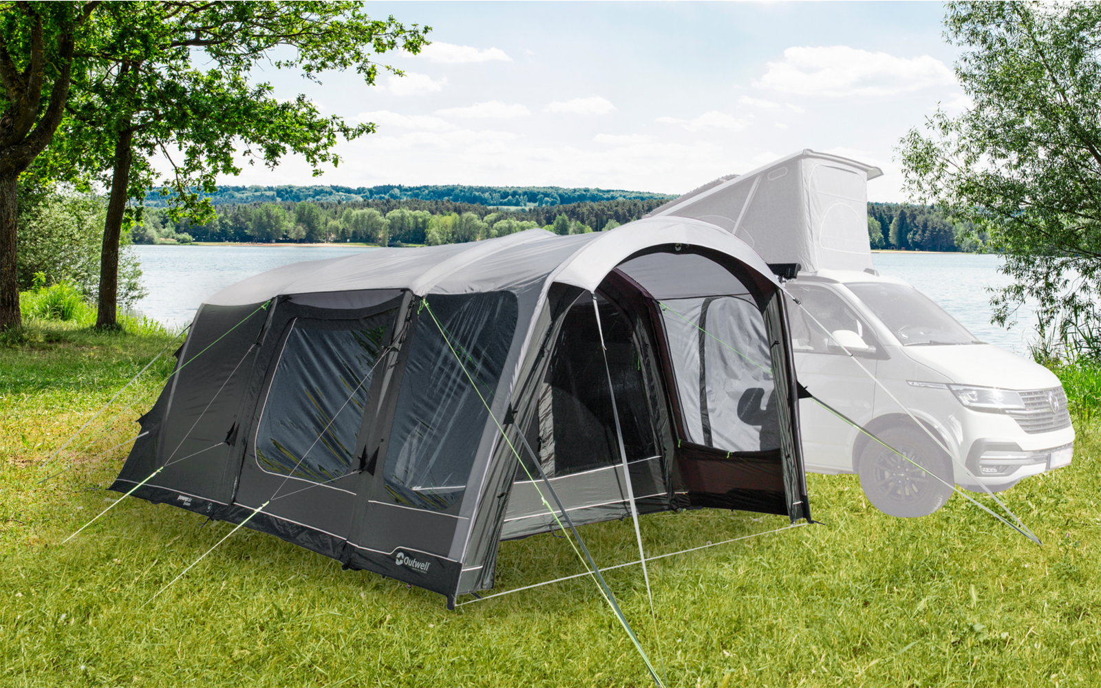 Aufblasbares Vorzelt an einem Wohnmobil auf einer grünen Wiese mit Bäumen im Hintergrund