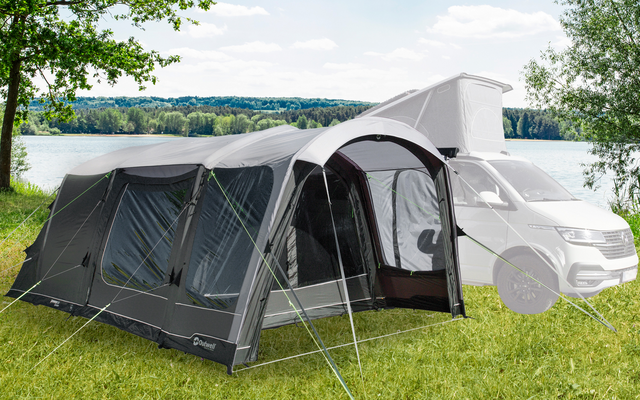 Aufblasbares Vorzelt an einem Wohnmobil auf einer grünen Wiese mit Bäumen im Hintergrund