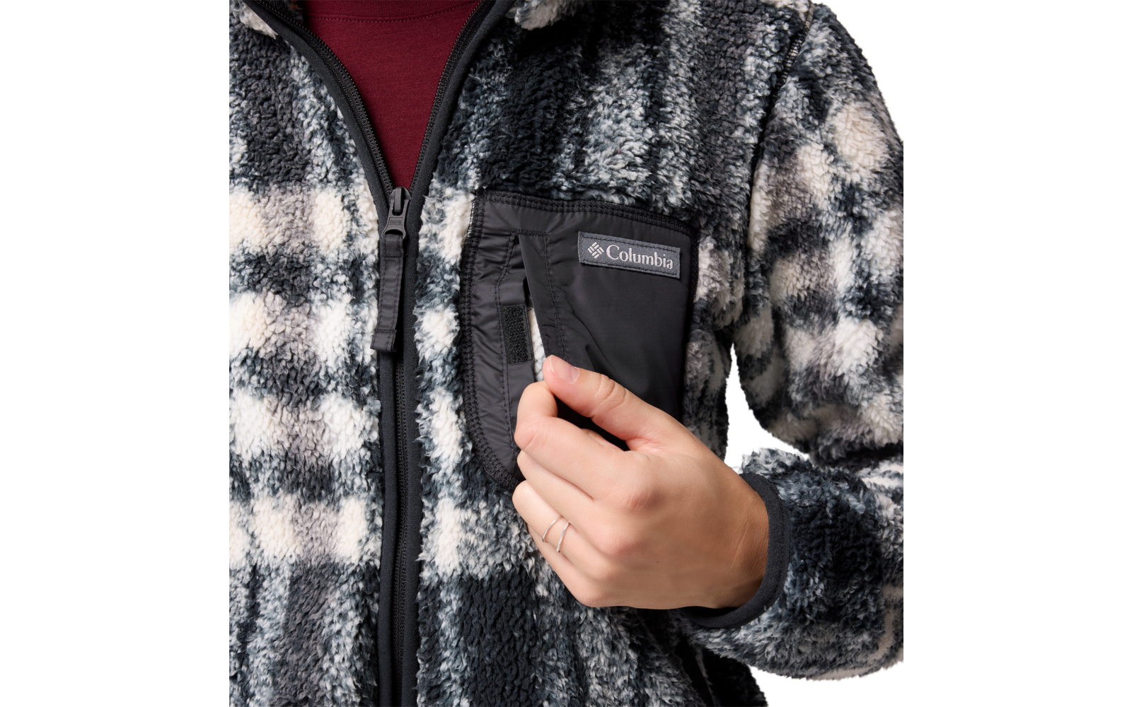 Mann zieht schwarzen Gegenstand aus einer Brusttasche einer karierten Jacke