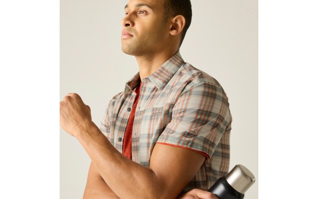 Person in kariertem kurzärmligen Hemd hält eine Thermoskanne und blickt nach oben rechts