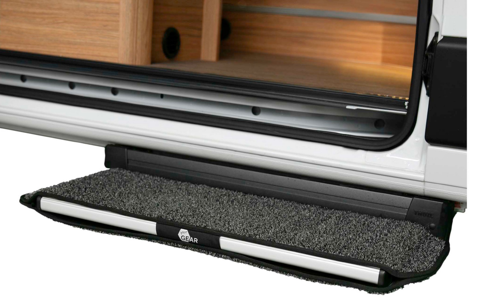 Geöffnete Seitentür eines Fahrzeugs, ausgeklappte dunkelgraue, mit Teppich bezogene Trittstufe, sichtbarer Holzinnenausbau