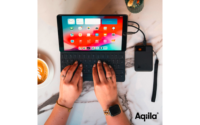 Handen bedienen een tablet op een witte tafel, naast een kop koffie en een zwarte externe schijf