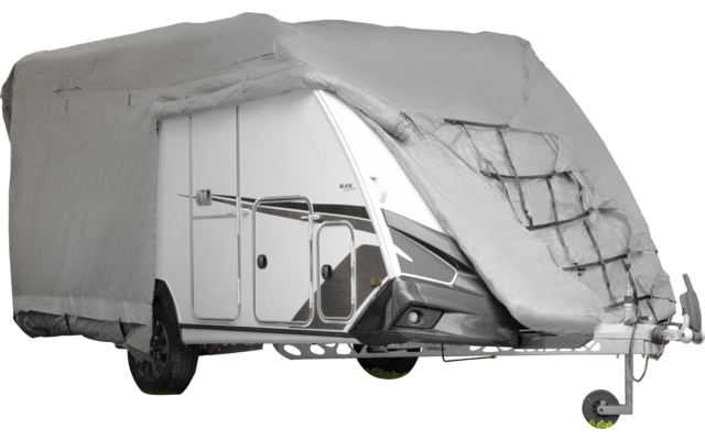 Caravana blanca parcialmente cubierta por una lona gris, puerta frontal, rueda y enganche de remolque visibles
