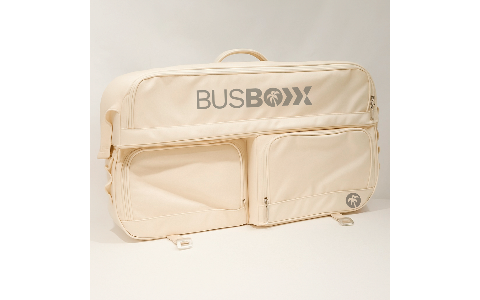 Sac beige souple avec poignée, deux poches avant zippées et inscription grise "BUSBOXX" sur fond neutre