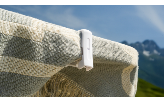 Weißer Klammer hält eine beige Stoffplane an einer Leine, blauer Himmel im Hintergrund