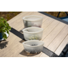 Three translucent plastic bowls in a row on a wooden outdoor table; front contains dark berries, middle contains green grapes, back contains red fruit
