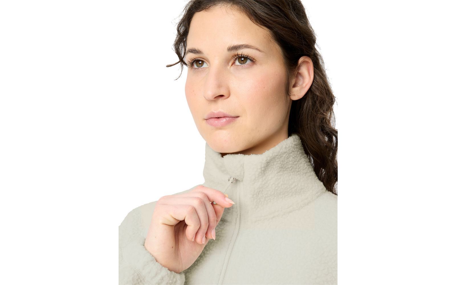 Close-up of a person with hair pulled back, holding the zipper pull of a light-colored fleece jacket at the chin, white background