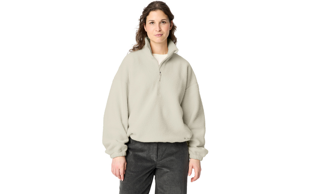 Woman standing facing the camera against a white background, wearing a light beige fleece quarter-zip and dark pants