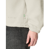 Hand of a person beside a cream fleece jacket with drawcord and zipper; dark gray corduroy pants visible below
