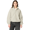 Woman standing facing the camera against a white background, wearing a light beige fleece quarter-zip and dark pants