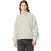 Person standing facing the camera against a white background, wearing a light beige fleece pullover with stand collar and quarter zipper, long sleeves, relaxed fit, dark trousers, hands visible at sides