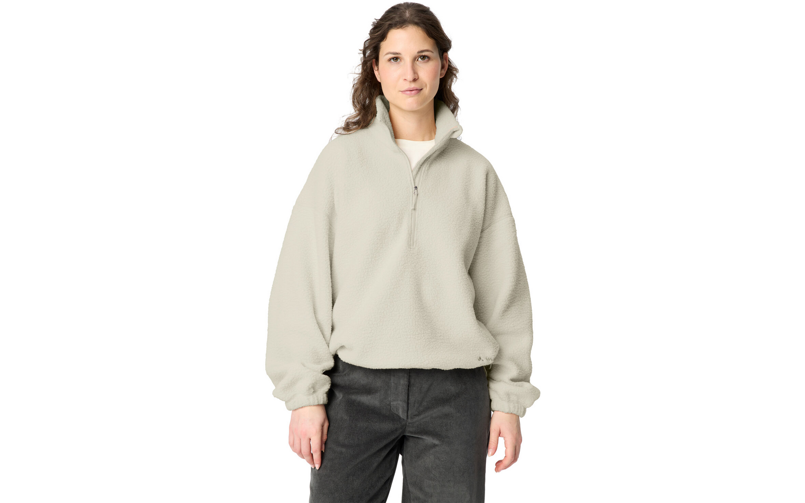 Woman standing facing the camera against a white background, wearing a light beige fleece quarter-zip and dark pants