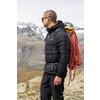 Mann mit Rucksack und Kletterseil vor Berglandschaft mit Schnee