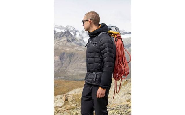 Mann mit Rucksack und Kletterseil vor Berglandschaft mit Schnee