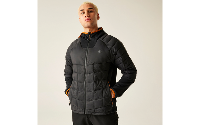 Mann mit kurzen Haaren trägt eine schwarze Steppjacke und steht vor einem hellen Hintergrund