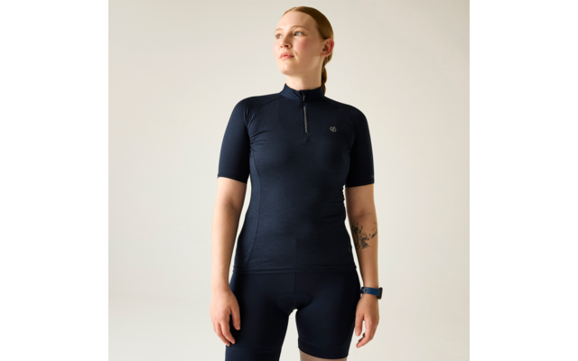 Person mit zusammengebundenem Haar, trägt dunkelblaues kurzärmeliges Trikot mit Reißverschluss und dunkelblaue Fahrradhose, Armbanduhr am Handgelenk, Tattoo am Unterarm sichtbar, Blick nach oben rechts