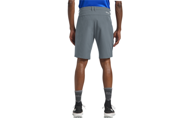 Achteraanzicht van een persoon van taille tot kuit, grijze knielange korte broek, blauwe shirtzoom, grijze sokken met patroon, zwarte sportschoenen met witte zolen, witte achtergrond