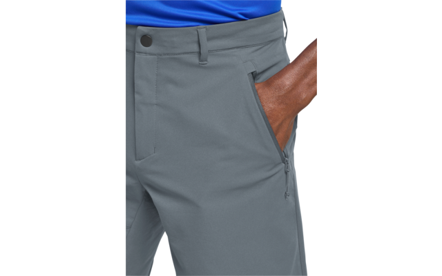 Onderlichaam van een persoon met een blauw bovenstuk en grijze broek, rechterhand in een ritssluiting-zijzak