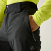 Mano en el bolsillo lateral de unos pantalones negros; cremallera, botones y velcro visibles en la cintura; encima, una camiseta de manga larga amarillo neón