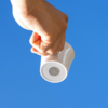 Hand hält weiße Tasse vor blauem Himmel