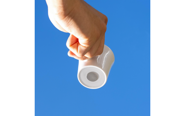 Hand hält weiße Tasse vor blauem Himmel