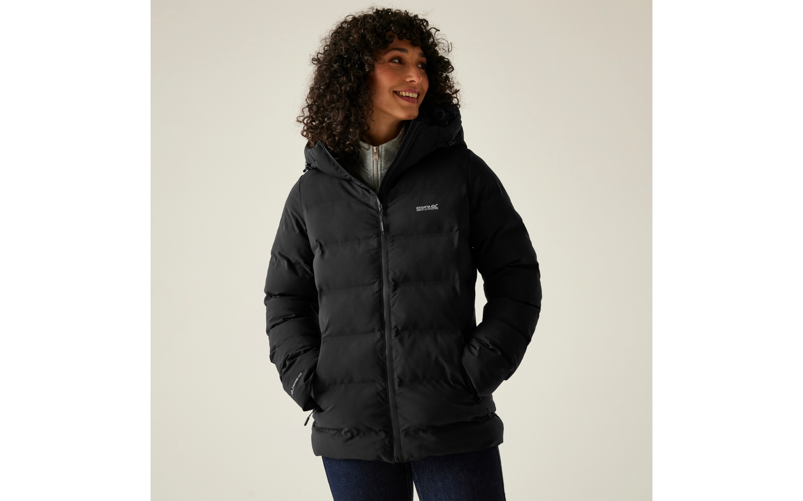Frau mit lockigen Haaren trägt eine schwarze Winterjacke und lächelt