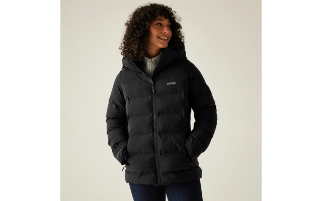 Frau mit lockigen Haaren trägt eine schwarze Winterjacke und lächelt