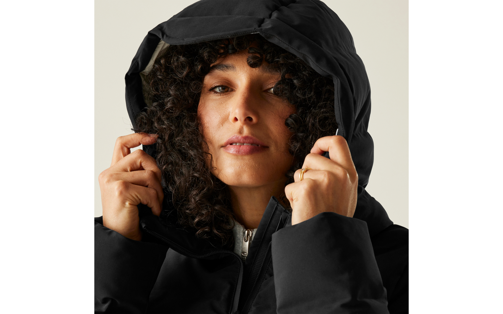 Frau mit lockigem Haar, die eine schwarze Kapuzenjacke anzieht