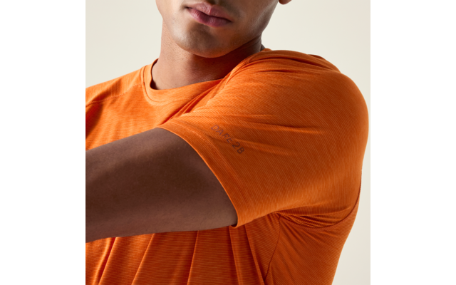 Gros plan sur un torse et un bras en t-shirt orange, partie inférieure du visage visible