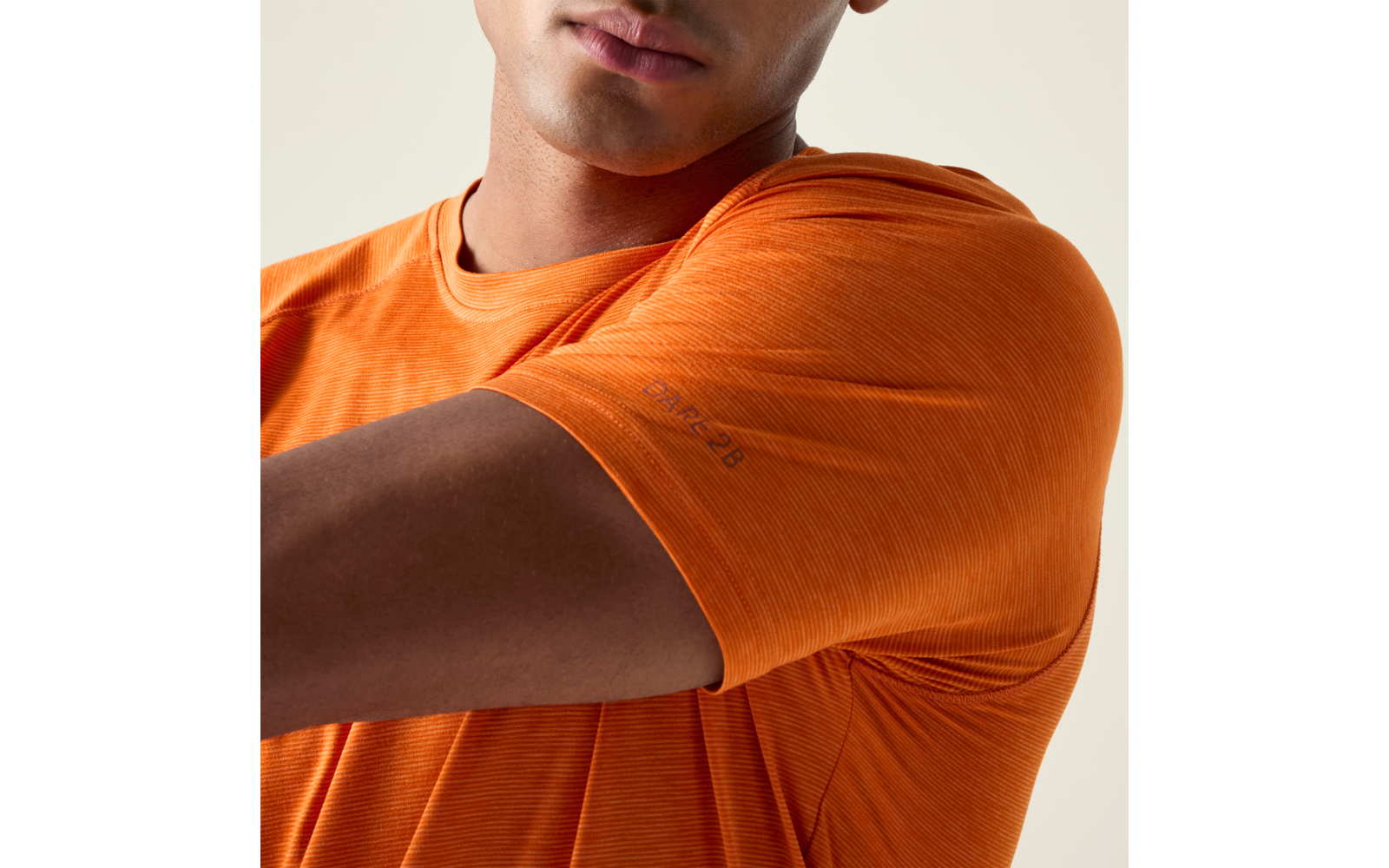 Gros plan sur un torse et un bras en t-shirt orange, partie inférieure du visage visible