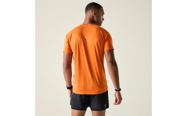 Personne de dos portant un t‑shirt orange à manches courtes et un short de sport noir, cheveux courts, bracelets noirs aux deux poignets, debout devant un fond clair uni, regarde vers la droite