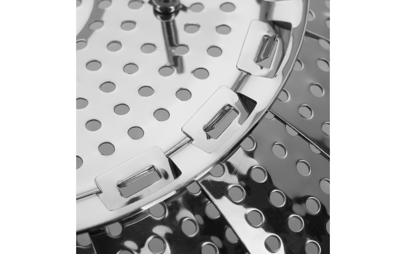 Nahaufnahme glänzender, perforierter Metallplatten mit runden Löchern, gebogenen Metalllaschen und einem zentralen Stift
