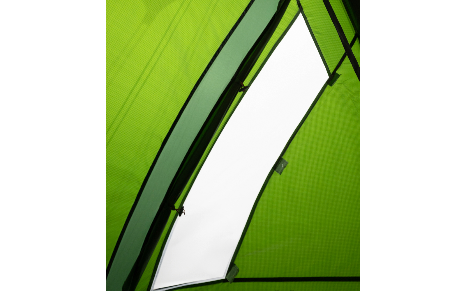 Innenraum eines grünen Zelts mit schrägem weißem, durchscheinendem Fenster und sichtbarem Reißverschluss