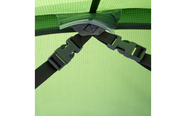 Grünes, kariertes Gewebe im Hintergrund; zwei schwarze Gurte mit Steckverschlüssen treffen an einem grauen Stoffpatch mit dreieckiger Naht; gebogene transparente Kunststoffplatte am oberen Rand