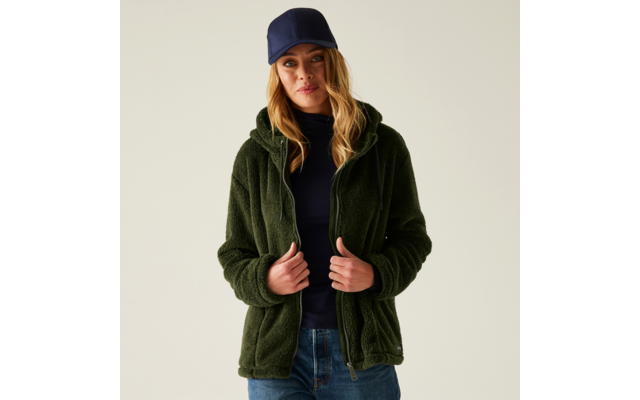 Frau mit blonden Haaren, die eine grüne Jacke und eine blaue Mütze trägt