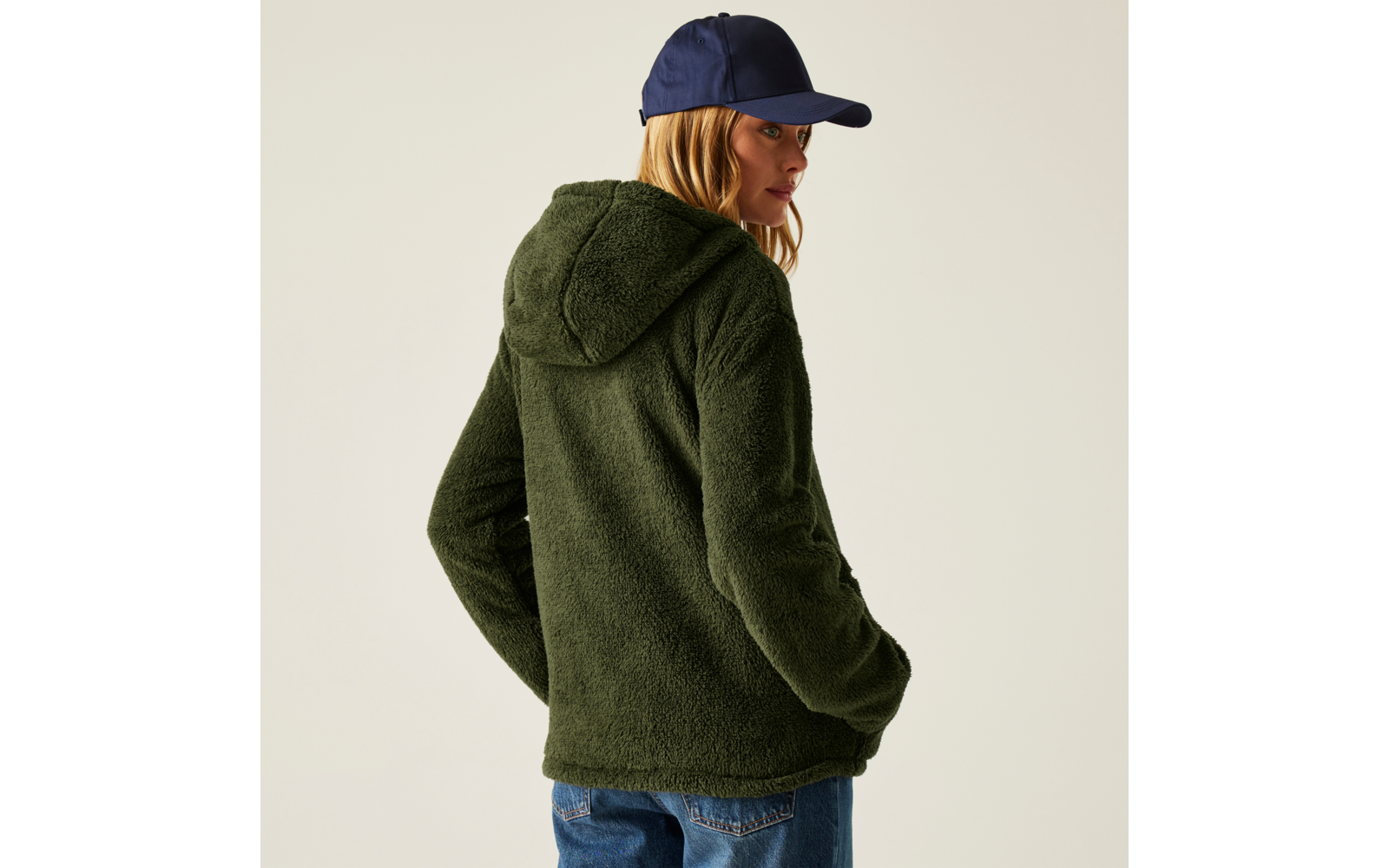 Person trägt grüne Kapuzenjacke und blaue Kappe, Blick nach links